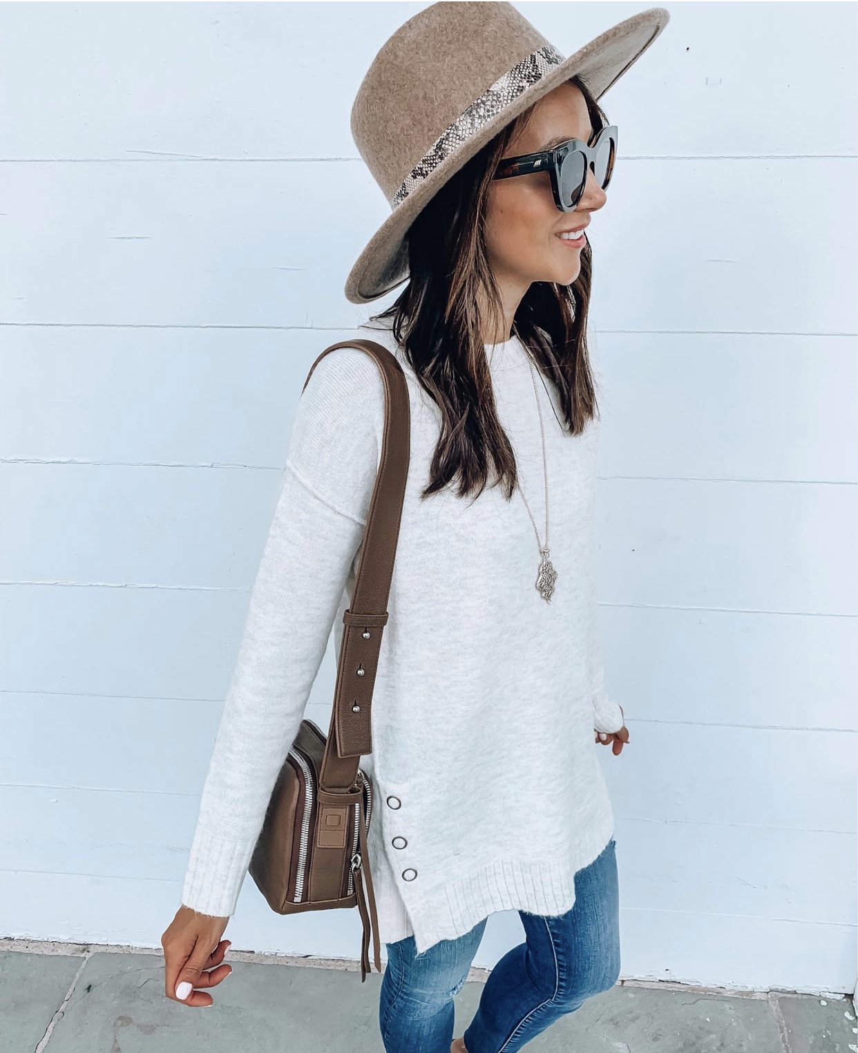 woman with hat and wearing tunic sweater and jeans