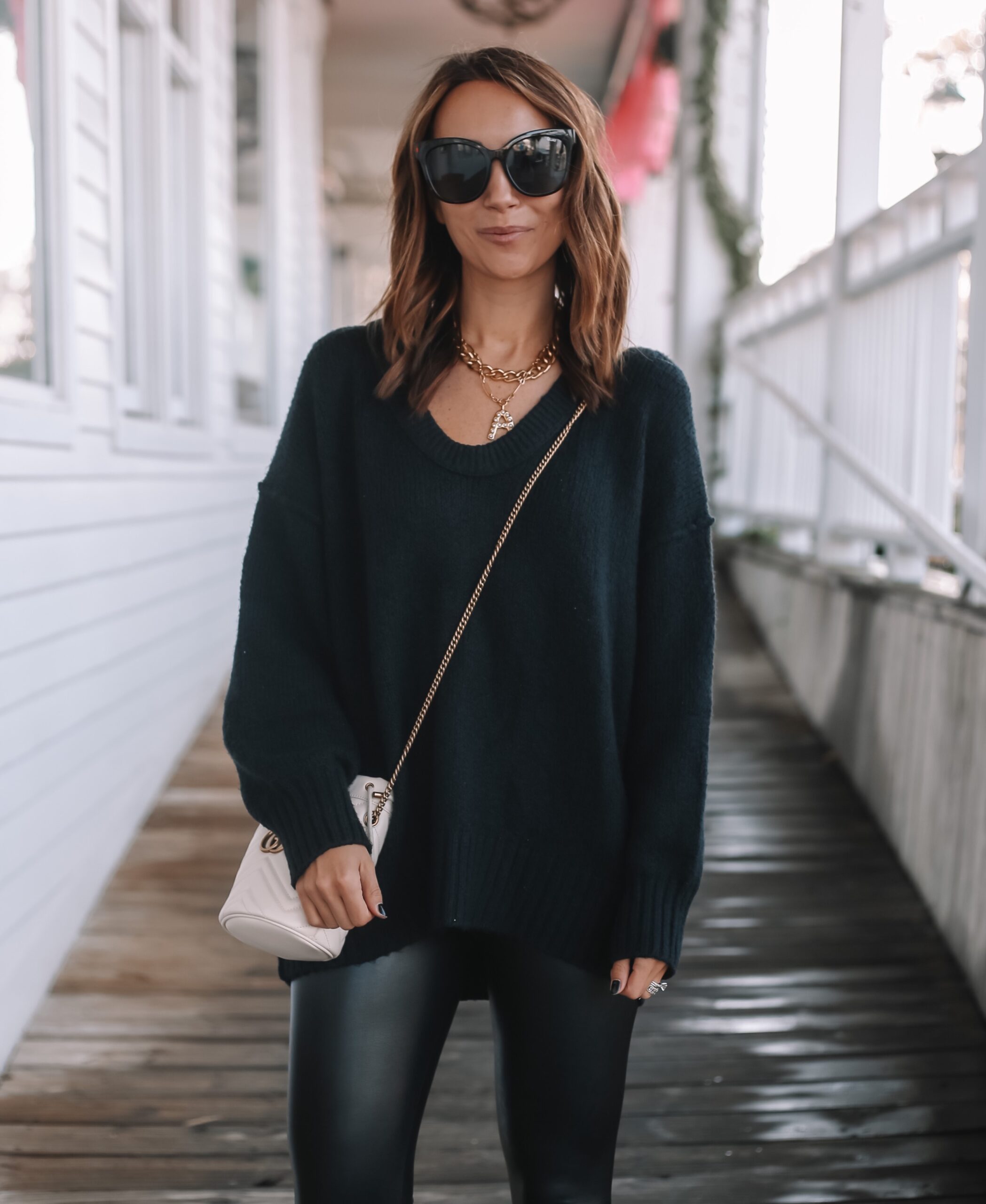 Trendy woman in an oversized grey sweater and black leather leggings