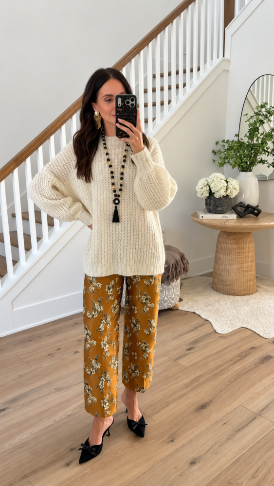 Oversized cream knit sweater paired with mustard yellow floral wide leg pants and black bow heels for a comfortable Thanksgiving outfit.