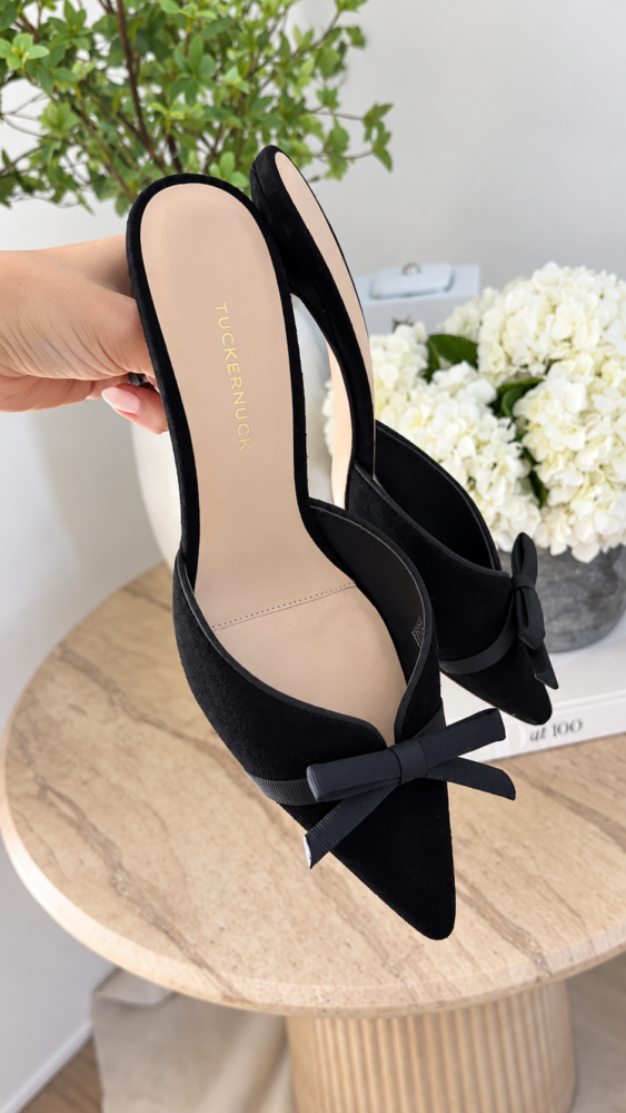 Black suede Tuckernuck heels with delicate bow details and pointed toes, perfect for Christmas parties and holiday outfits.